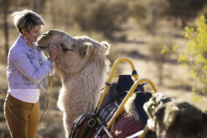 Woman petting a camel at Uluru on a camel tour